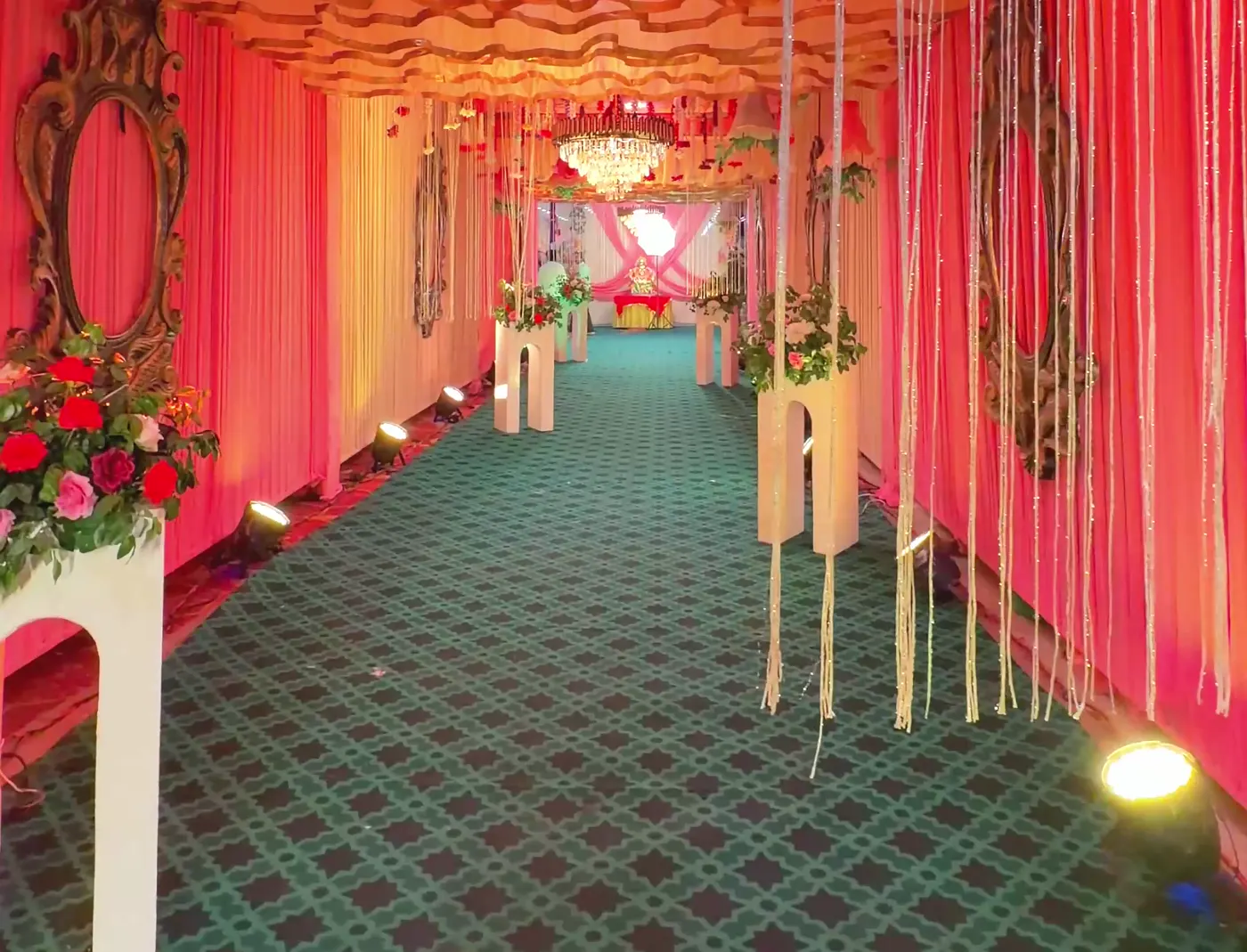 Draped event entrance with flowers and lit pathway