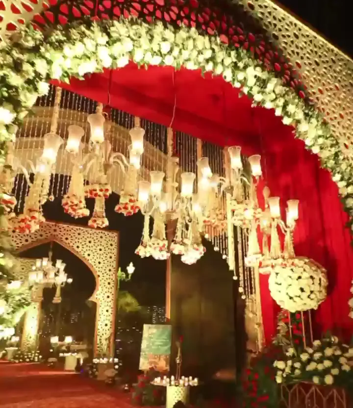 Floral gateway with hanging chandeliers and red drapes