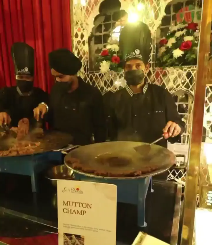 Chefs preparing food on a large griddle at a live counter