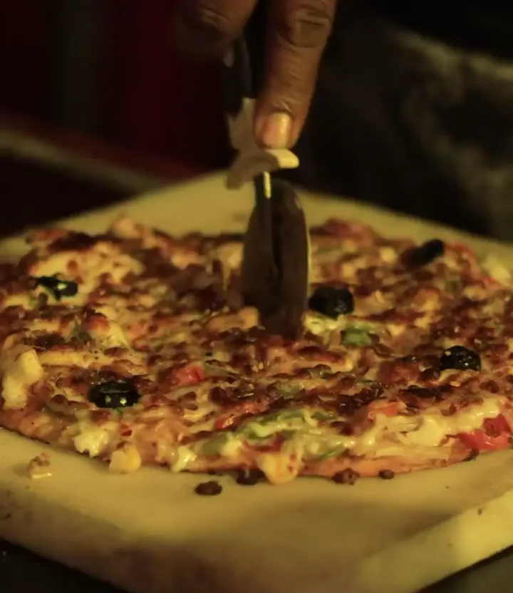 Pizza being sliced on a board
